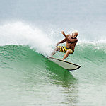 An elderly man wave surfing.